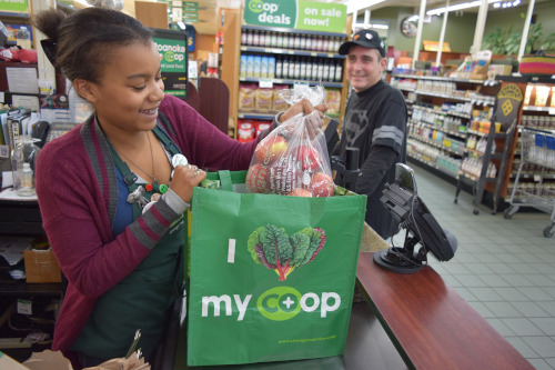 A woman bagging groceries at the co-op checkout counter